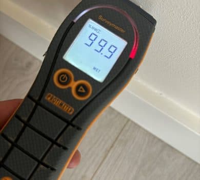 Moisture meter held against an interior wall